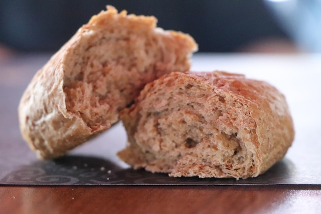 Foto versgebakken klein brood geheel en twee helften op houten bovenaanzicht als achtergrond