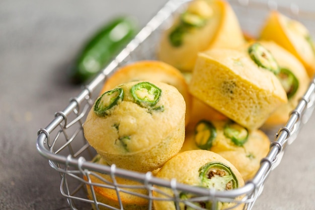 Versgebakken maïsbroodmuffins met pittige jalapenopeper in een mand met draad.