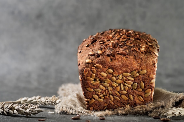 Versgebakken tarwe- en roggebrood met zaden op jute, close-up met selectieve focus. Gefermenteerd gezond brood, grijze achtergrond met ruimte voor tekst