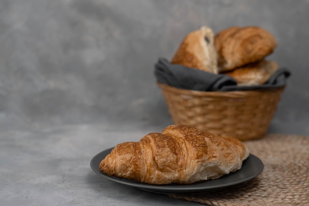 Versgebakken zelfgemaakte croissants voor het ontbijt. Traditionele en volkoren croissant in een grijze plaat op een betonnen of stenen ondergrond. Ruimte kopiëren.