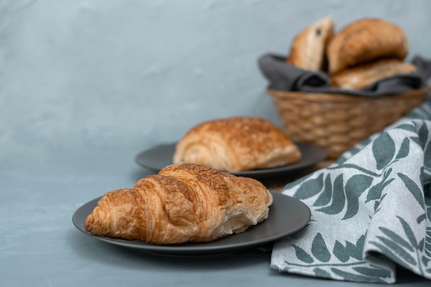 Versgebakken zelfgemaakte croissants voor het ontbijt. Traditionele en volkoren croissant in een grijze plaat op een betonnen of stenen ondergrond.