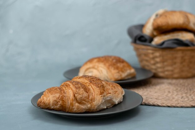 Versgebakken zelfgemaakte croissants voor het ontbijt. Traditionele en volkoren croissant in een grijze plaat op een betonnen of stenen ondergrond.