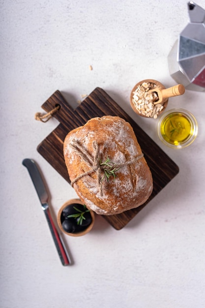 Versgebakken zuurdesem ciabatta ambachtelijk brood met olijven en rozemarijn op een witte abstracte tafel