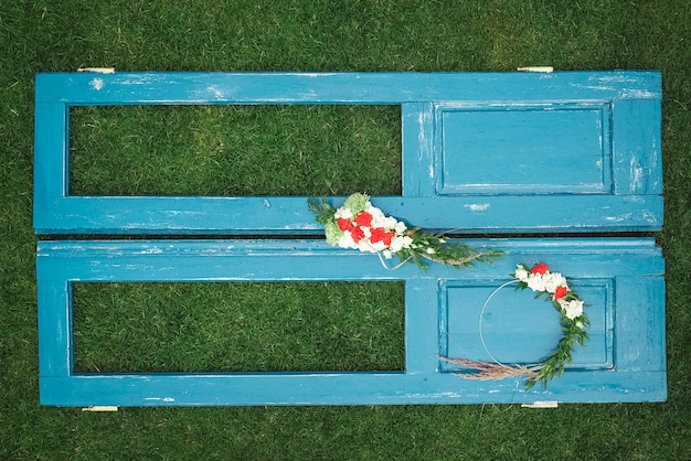 Versierde krans van bloemenbladeren en droog gras op een houten blauwe deurachtergrond