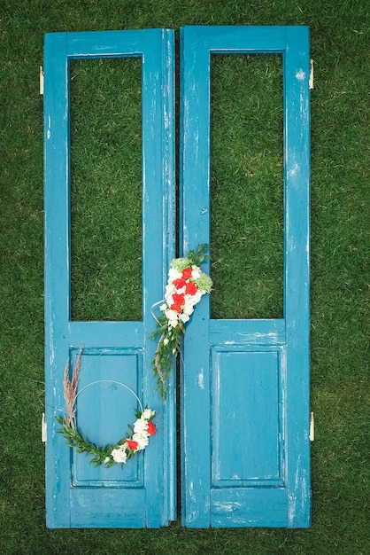 Versierde krans van bloemenbladeren en droog gras op een houten blauwe deurachtergrond