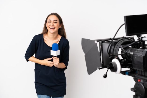 Verslaggeversvrouw die een microfoon houden en nieuws rapporteren dat op wit wordt geïsoleerd dat veel glimlacht