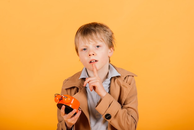 Verslapen. Bezorgd wakker tienerjongen met wekker is geschokt omdat het te laat is