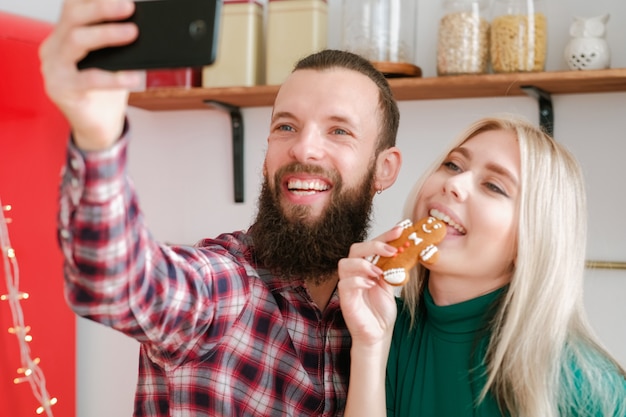 Verslaving aan sociale media. Leuk paar dat smartphone gebruikt om selfie met peperkoekman in keuken te nemen.