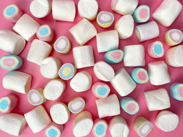 Foto verspreide gekleurde marshmallows op een roze achtergrond