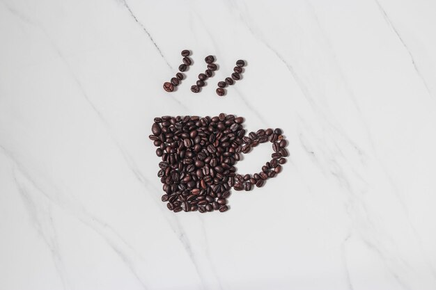 Verspreide koffiebonen en de kop van de koffieespresso op marmeren achtergrond