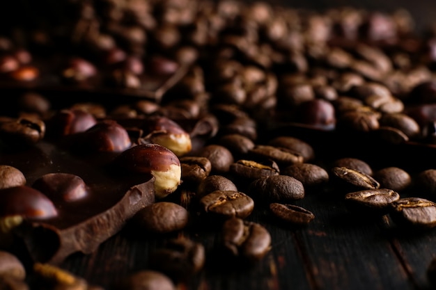 Verspreide koffiebonen en zwarte chocolade op een houten tafel.