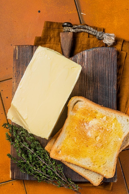 Verspreiding van boter op toast met mes Oranje achtergrond Bovenaanzicht