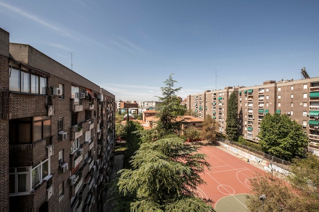 Verstedelijkingsgevels van woongebouwen omgeven door bomen en met basketbalvelden