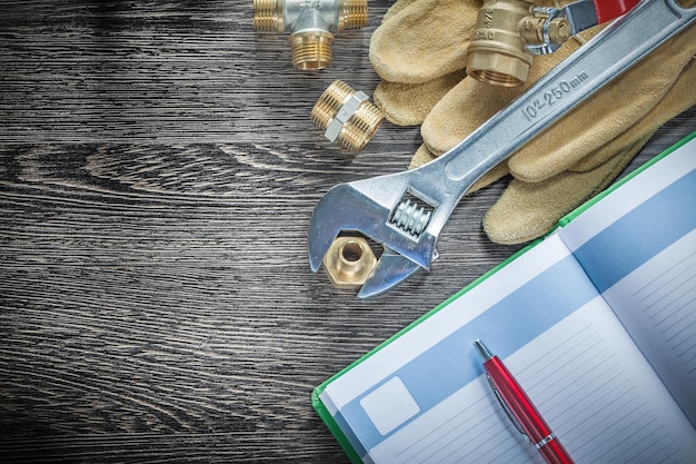 Verstelbare moersleutel waterklep buisfittingen lederen beschermende handschoenen notitieblok pen.