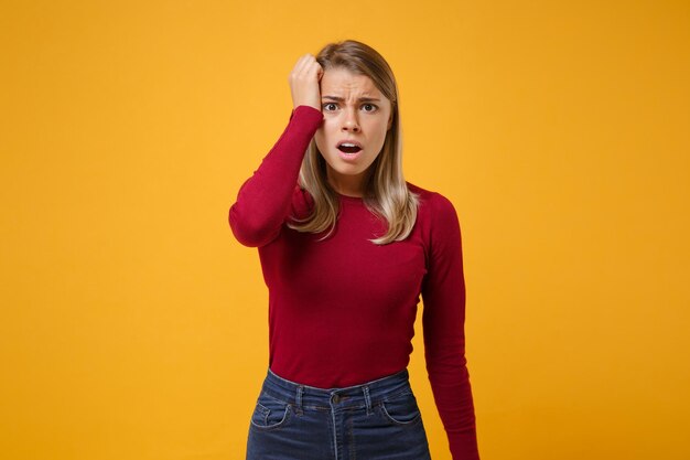 Foto verstoorde jonge blonde vrouw in vrijetijdskleding poseren geïsoleerd op geeloranje muur achtergrond studio portret. mensen oprechte emoties levensstijl concept. mock up kopie ruimte. hand op hoofd zetten.