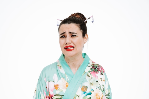 Verstoorde vrouw in traditionele Japanse kimono met droevige uitdrukking die een wrange mond op wit maakt