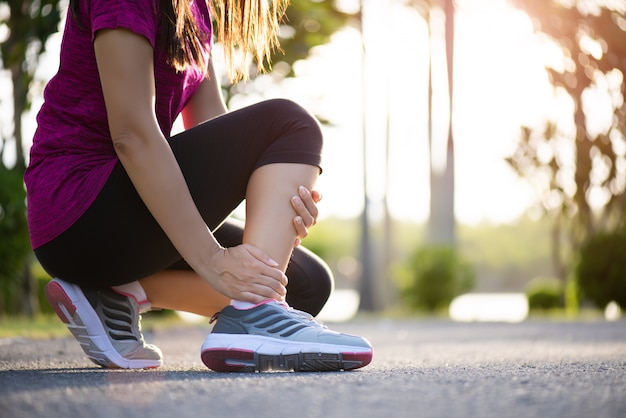 Verstuikte enkel. jonge vrouw die lijden aan een enkelblessure tijdens het sporten