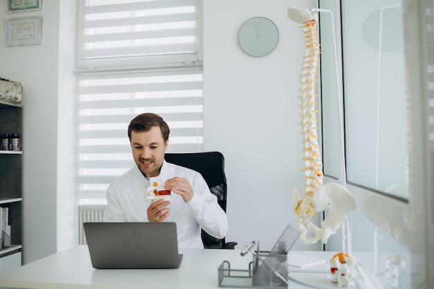 A vertebrologist doctor works on a camera behind a laptop