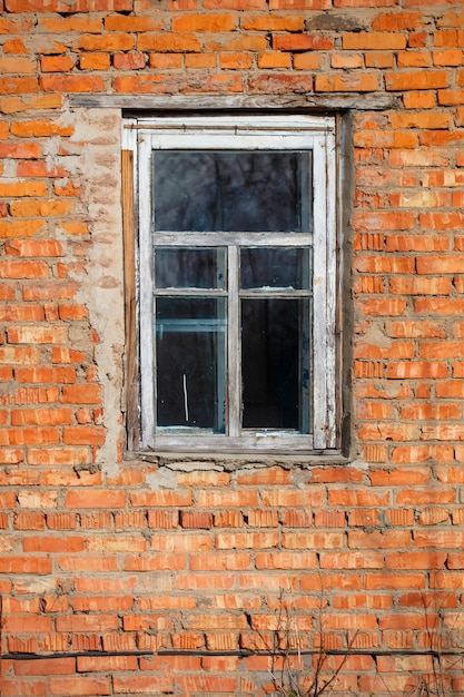 Verticaal bakstenen muur met een raam in een oud rustiek frame.