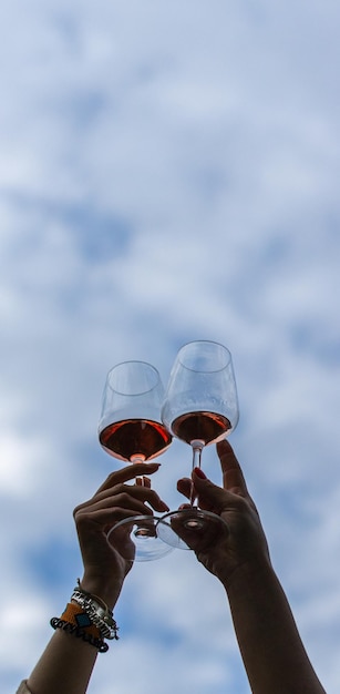 Verticaal beeld van de handen van een jong vrouwelijk stel dat roostert met wijnglazen
