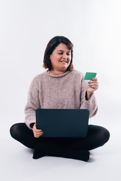 Verticaal beeld van een vrouw die naar een creditcard kijkt en een pc gebruikt. Internet winkelconcept