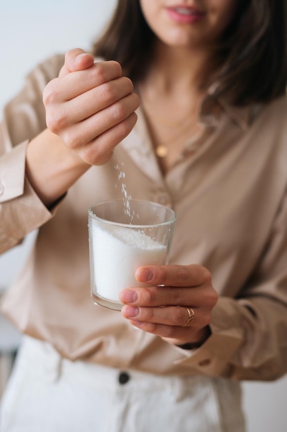 Verticaal bijgesneden schot van vrouwelijke ambachtsman die droog mengsel met de hand giet in het meten van transparant glas voor het maken van een kaarsenbouwmengsel. proces van het maken van handgemaakte natuurlijke kaars op workshop.