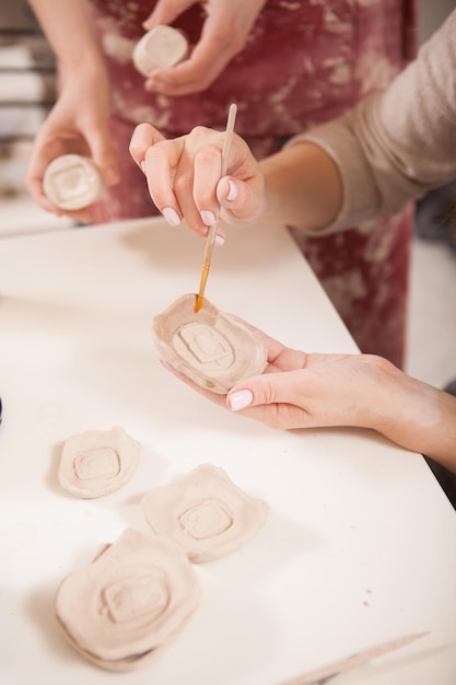 Verticaal bijgesneden shot van onherkenbare vrouwen die met klei aan het werk zijn bij pottenbakken