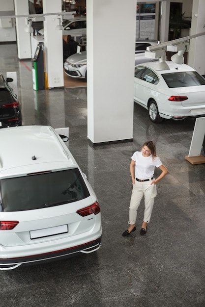 Verticaal bovenaanzicht van een vrouw die een nieuwe auto kiest om te kopen bij een autodealer