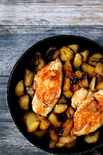 Verticaal bovenaanzicht van gebakken vis en aardappelen in een pan op een houten ondergrond