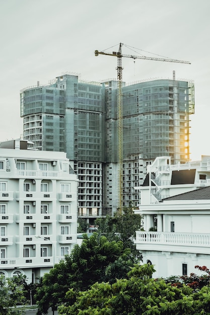 VERTICAAL groot woon- of kantoorgebouw met meerdere verdiepingen in aanbouw zonsopgang hemelachtergrond torenkranen Onroerend goed bedrijf kopen investeren in appartementen in het buitenland hypotheek