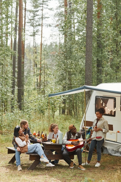 Verticaal groothoekbeeld bij diverse groep jonge mensen die buiten picknicken tijdens het kamperen met...