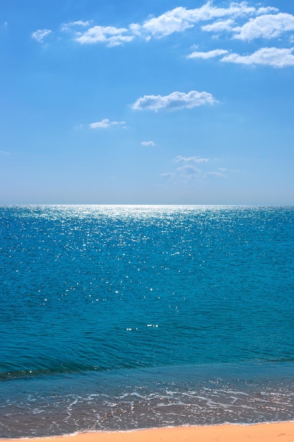 Verticaal Kalm zeegezicht Blauwe zee met zandstrand en blauwe lucht met wolken aan de horizon