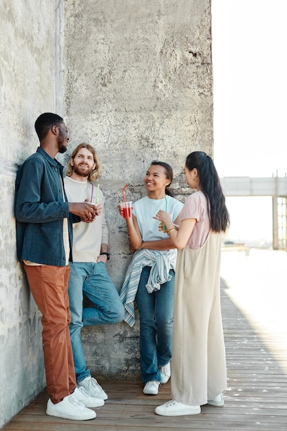 Verticaal portret over de volledige lengte van een diverse groep jongeren die chatten in een stedelijke stadsomgeving