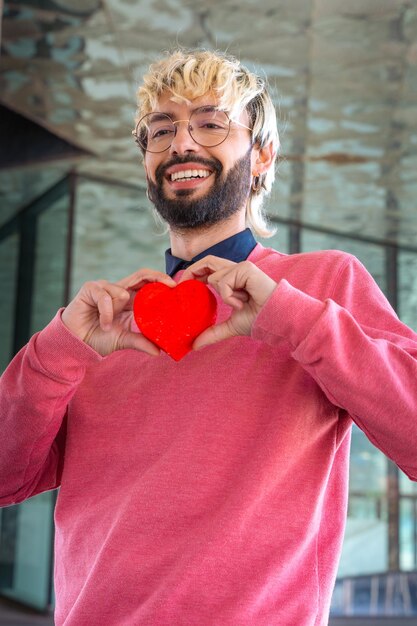 Foto verticaal portret van een glimlachende jonge man die een hartliefde vasthoudt