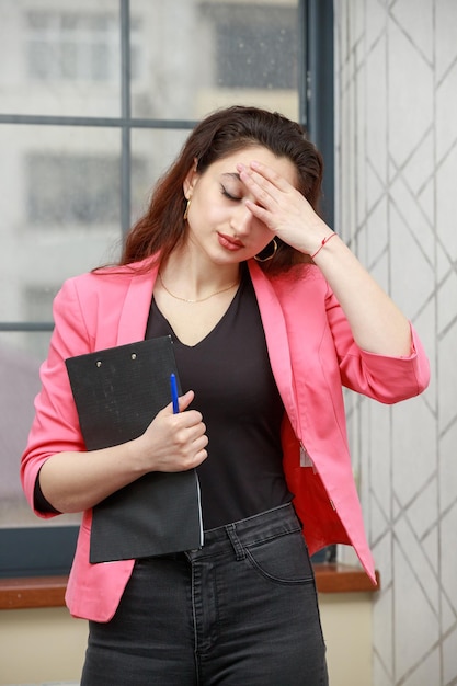 Verticaal portret van een jonge dame die zich moe voelt en haar hand op haar voorhoofd legt