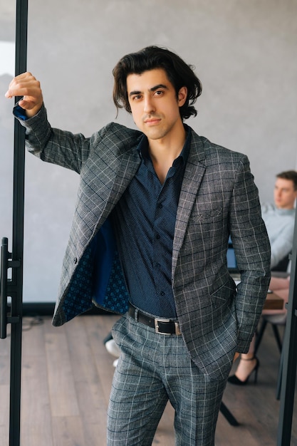 Verticaal portret van een knappe zakenman in een pak die in een moderne kantoorruimte staat en zelfverzekerd naar de camera kijkt Startup business team dat project bespreekt