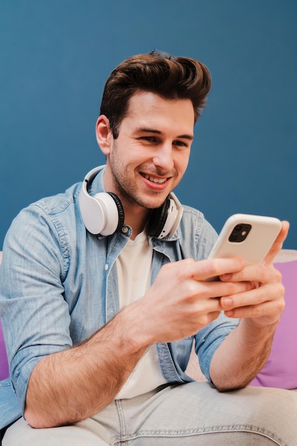 Verticaal portret van een tiener die plezier heeft met het surfen op het internet met een mobiele telefoon jonge man die een
