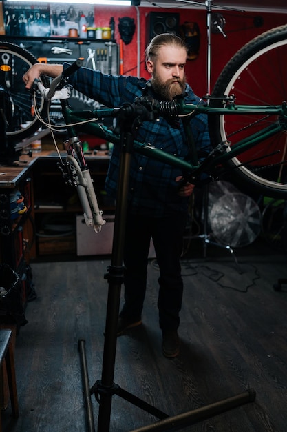 Verticaal portret van reparateur die kijkt naar achterverschuiver van mountainbike veranderende snelheden met behulp van stuurhendel die werkt in fietsenmaker