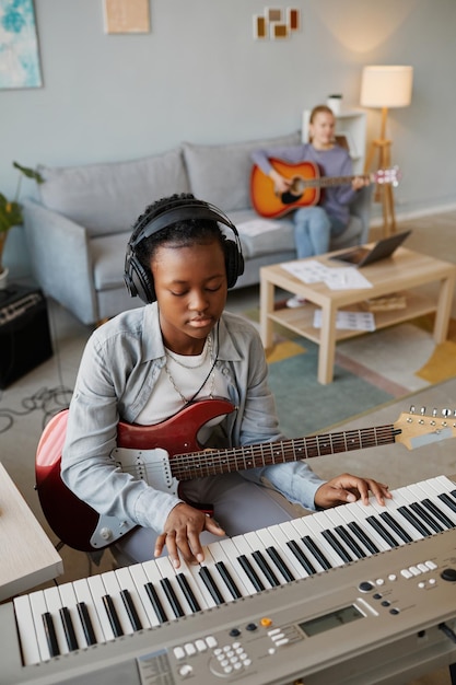 Verticaal portret van zwarte jonge vrouw die thuis muziek speelt en een koptelefoon draagt