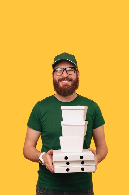 Foto verticaal schot van een glimlachende bezorger in het groen die wat lunchboxen vasthoudt