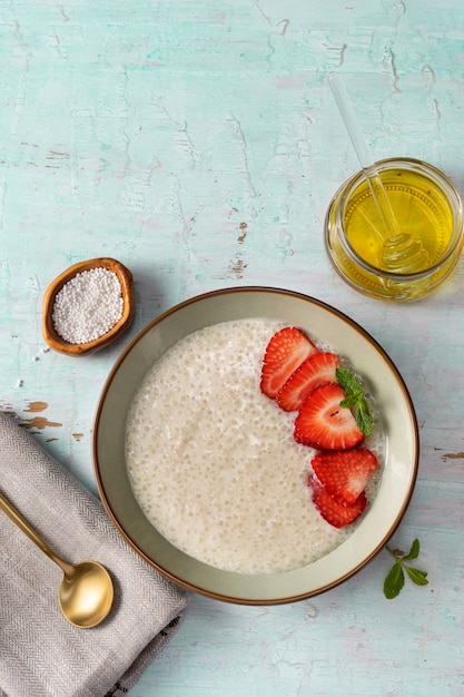 Verticaal schot van een plaat met vegan tapiocapudding op lichte turkooise achtergrond