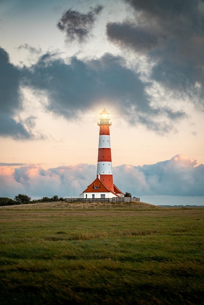 Verticaal schot van een vuurtoren in het veld tegen een bewolkte hemel in Westerhever, Duitsland