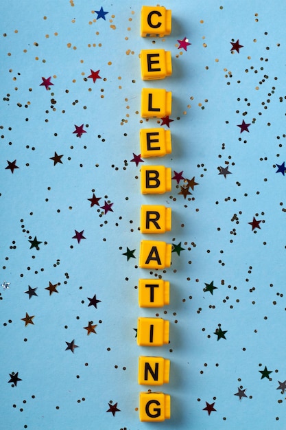 Verticaal schot van het vieren van woord gemaakt van gele letterblokjes