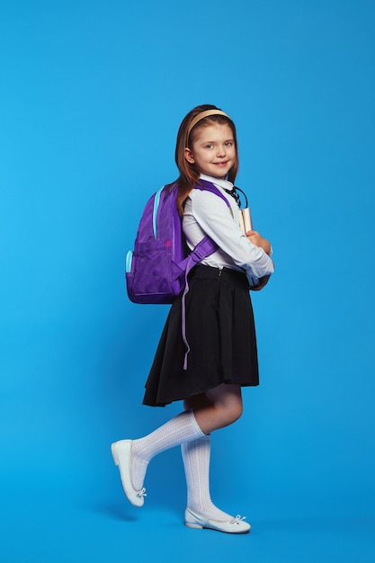 Verticaal schot van meisje met rugzak en schooluniform met boeken