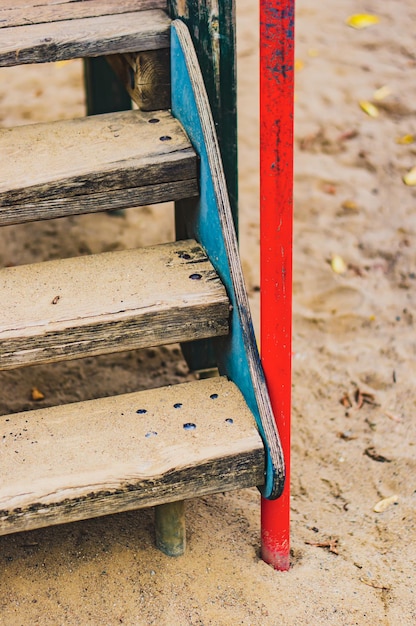 Verticaal schot van oude roestige houten trappen op de zanderige grond