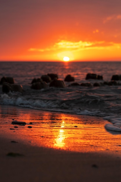 Verticaal schot van rotsen op het strand op een heldere zonsondergang hemelachtergrond