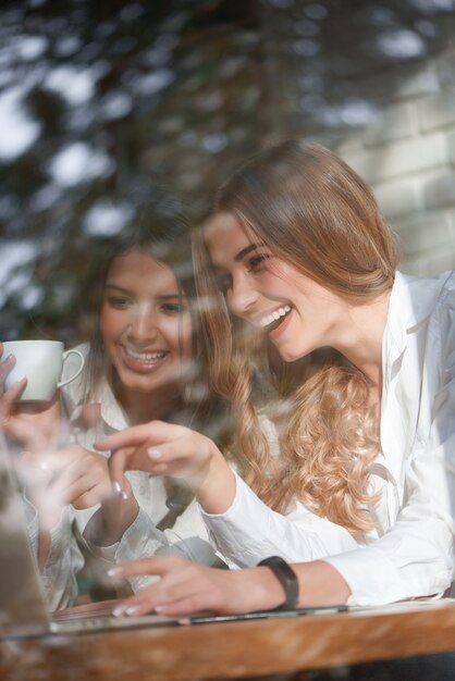 Verticaal schot van twee mooie gelukkige jonge vrouwen die laptp samen gebruiken bij de plaatselijke coffeeshop vriendschap vrienden communicatie zusters binding vrije tijd saamhorigheid emoties positiviteit internet.