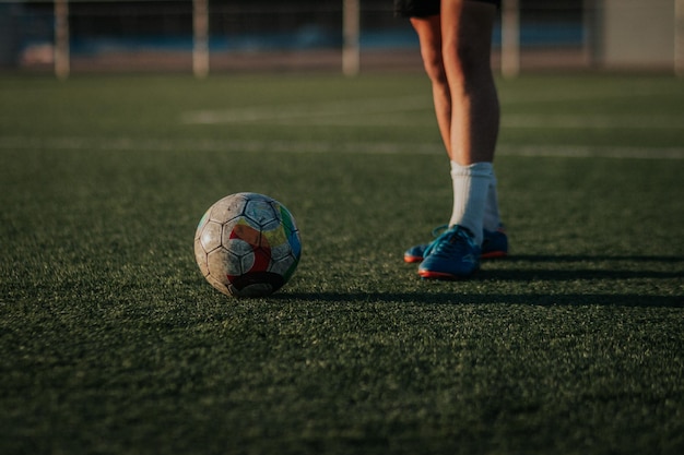 Verticaal schot van voetbal met de benen van de speler die wachten om hem te schoppen.