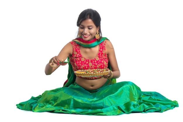 Foto verticaal, van, een, indiër, traditionele, meisje, vasthouden, diya, en, vervaardiging, rangoli, meisje, vieren, diwali, of, deepavali, met, vasthouden, olielamp, tijdens, festival van licht