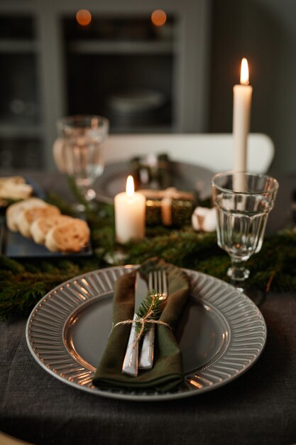 Vertical background image of black table setting decorated for christmas with candles lit copy space